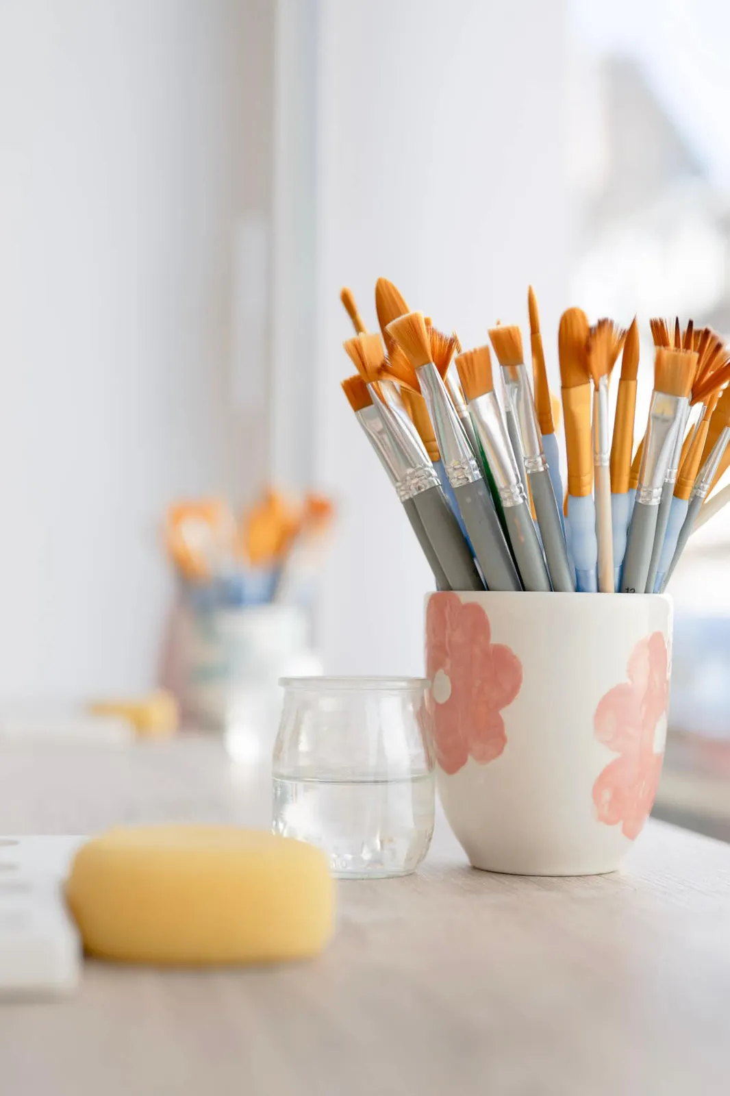 Pinceaux dans une tasse peinte de fleurs roses